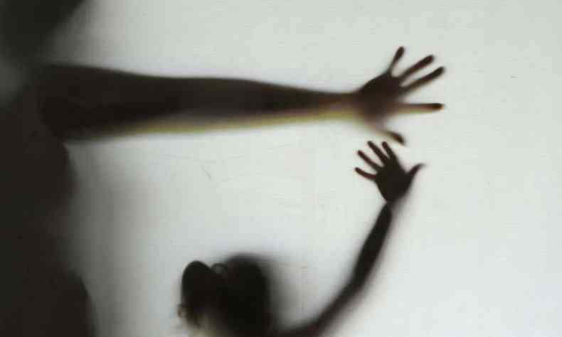 Foto ilustrativa de uma sombra em parede branca de uma criana sendo violentada por um adulto