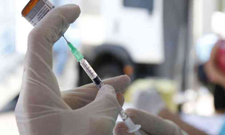Vacina sendo retirada do vidro de dose e alocada na seringa