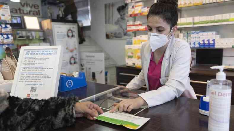Um farmacêutico mostra um teste de antígeno a uma pessoa na farmácia 'Las Gemelas', em 10 de janeiro de 2022, em Madri, Espanha
