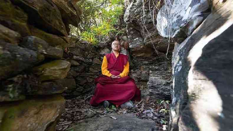 Rinpoche em um refgio cercado por pedras no meio da floresta