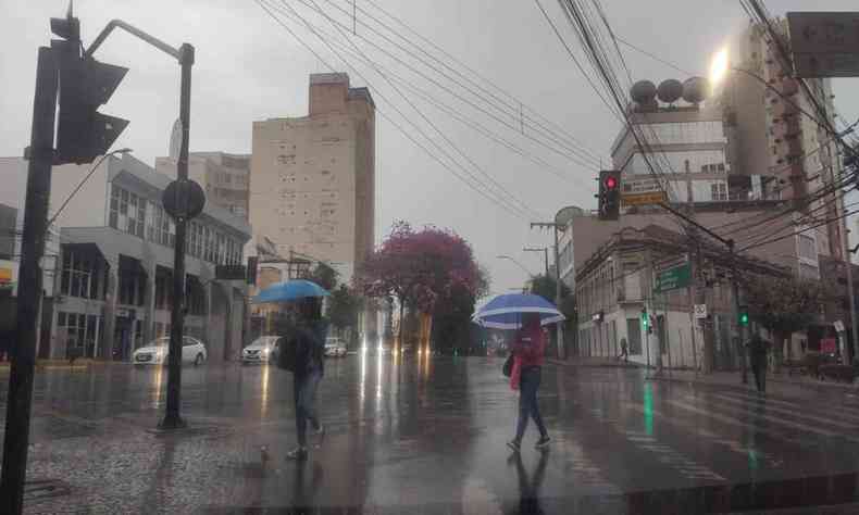 pessoas se protegendo da chuva que atinge a capital mineira 