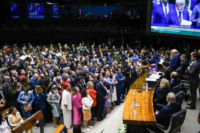 Lula toma posse no Plenrio da Cmara dos Deputados. Lula l um papel da mesa da Cmara enquanto uma multido de pessoas em roupas sociais o observa do plenrio