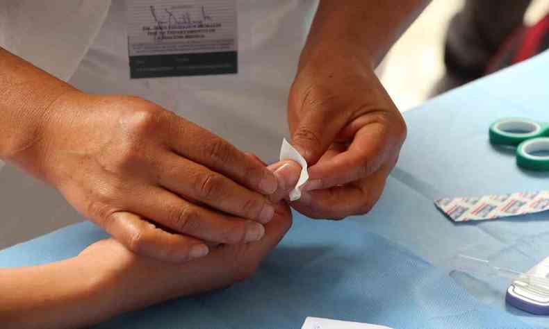 Enfermeira aplica teste no dedo de paciente