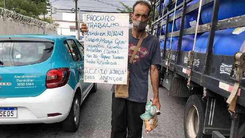 José Gonçalves Neto segurando placa pedindo ajuda entre carros