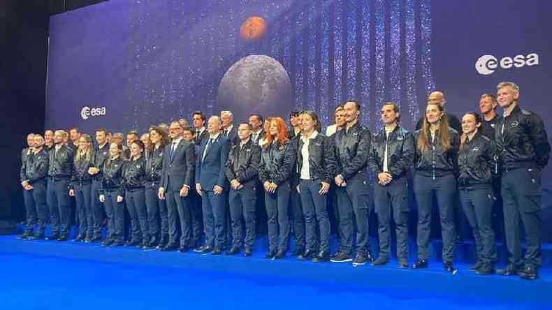 Homens e mulheres enfileirados em palco, posando para foto