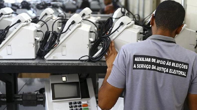 Homem manuseando urnas eletrnicas