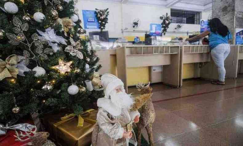 Na foto, agência central dos correios com decoração de natal; uma pessoa é atendida no balcão