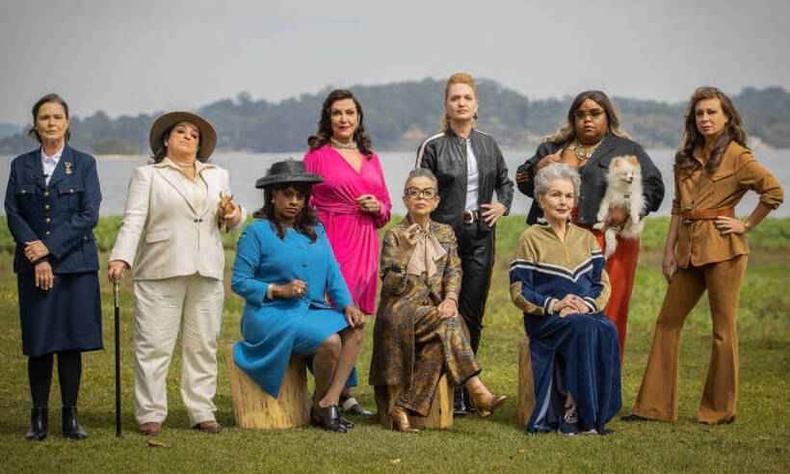 Nove atrizes do filme O Clube das Mulheres de Negcios olham desafiadoramente para a cmera, posando ao ar livre com um lago ao fundo
