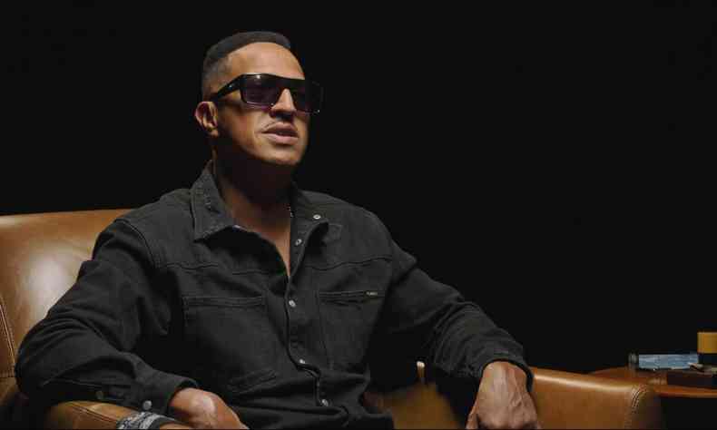 Mano Brown sentado em poltrona durante documentrio sobre o Racionais MCs