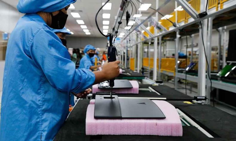 Uma mulher de uniforme azul manipulando um objeto, provavelmente instrumento de trabalho