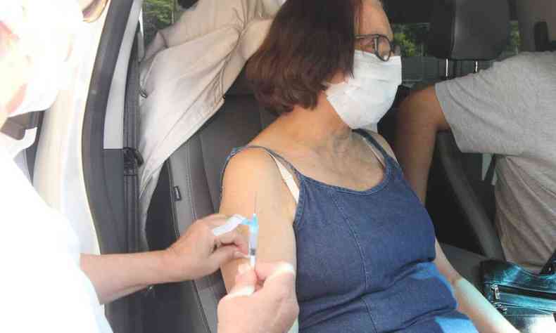Dentro de um carro, mulher recebe aplicao de dose de vacina no brao