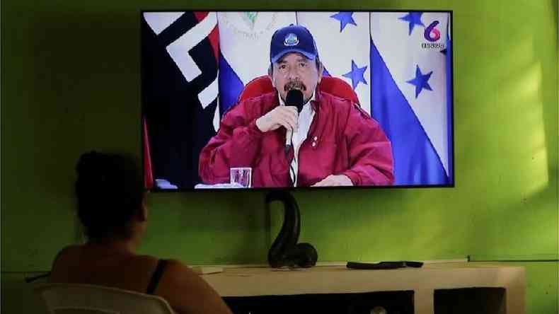 Mulher assiste à televisão, onde aparece Daniel Ortega fazendo um discurso