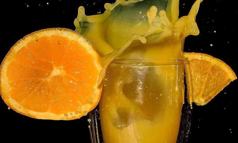 Copo com suco de laranja e a metade da fruta para enfeitar o copo