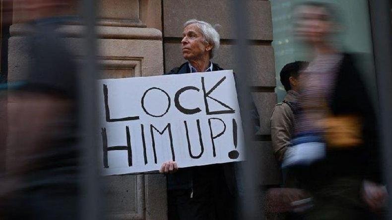 Manifestante perto da Trump Tower(foto: Getty Images) Manifestando segurando cartaz pedindo prisão de Trump perto da Trump Tower