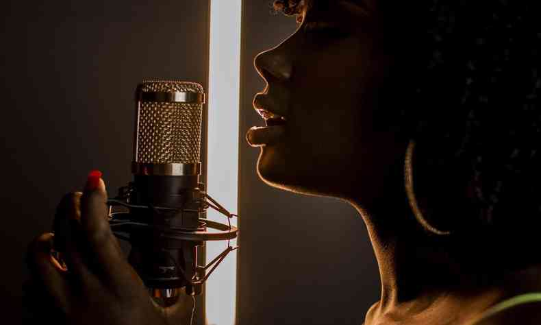 Cantora Keilla Jnia, vencedora do 'The Voice Brasil 2022', ao microfone em um estdio  meia luz