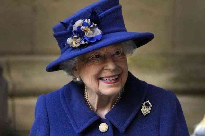 Sorridente e de roupa e chapu azul, a rainha Elizabeth II 
