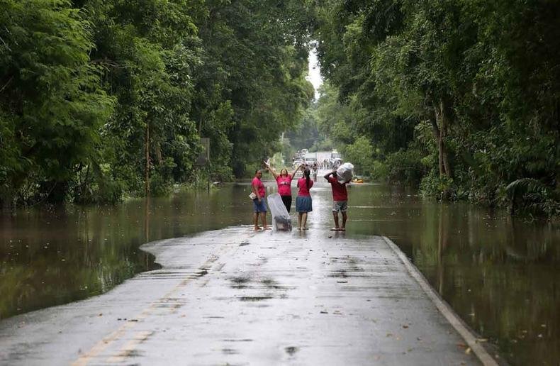 (foto: Camilla Souza/Gov.BA/AFP ) Moradores caminham em trecho alagado da BR-415, entre Itabuna e Ilhéus
