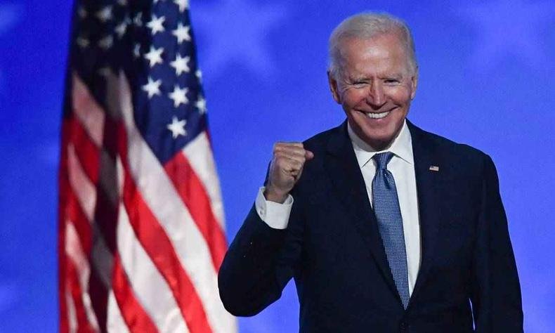Presidente americano Joe Biden sorri e levando o bra�o com as m�os fechadas