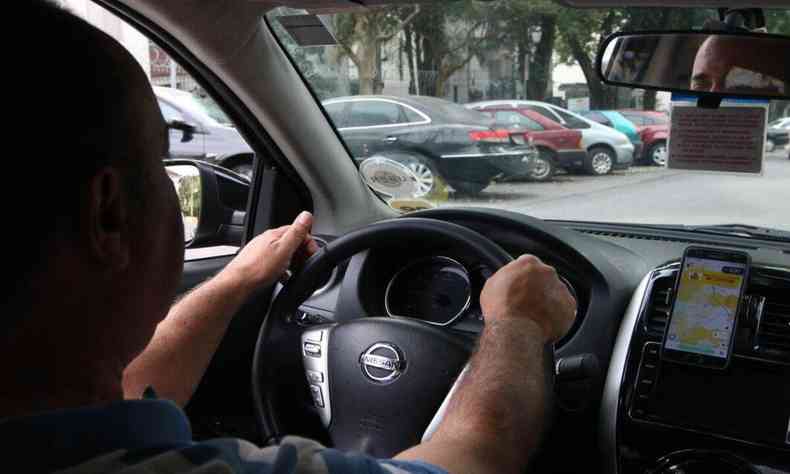 Motorista com as mos no volante do carro visto do banco de trs do veculo. 