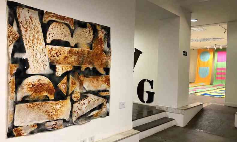 Pintura de João Diniz tem letras brancas e tons enferrujados sob fundo preto na exposição Poematéria: arquitetura da palavra