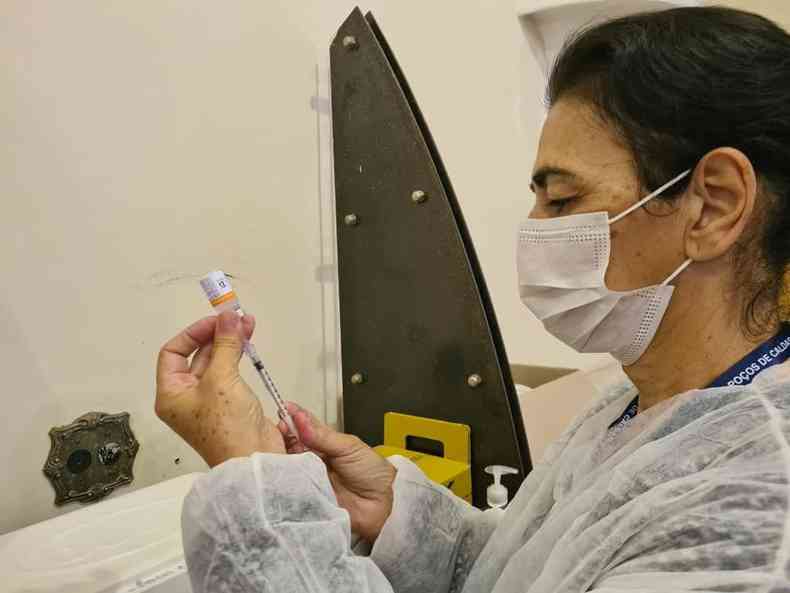 Mulher segurando uma seringa no posto de sade