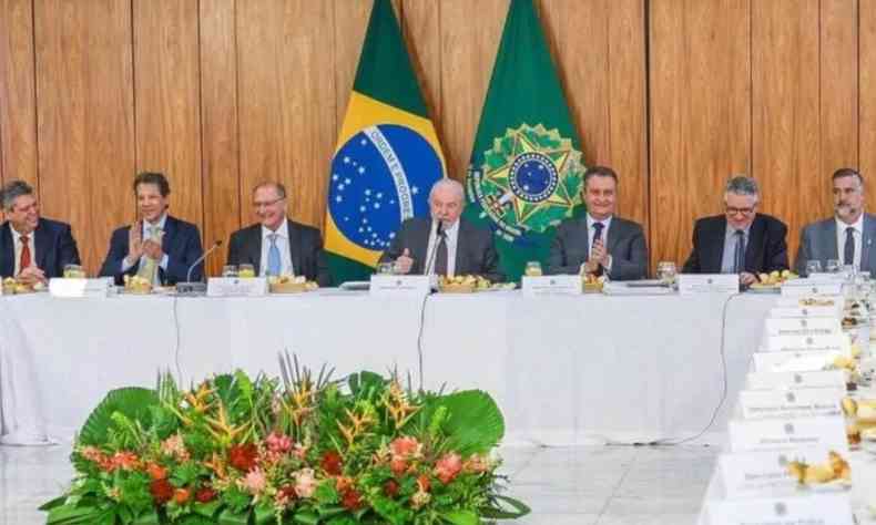 Lula em reunio com presidentes e lderes de partido. Ele est no centro da mesa e ao seu lado direito e esquerdo h trs homens, em cada lado. Ao fundo duas bandeiras, do Brasil e presidencial