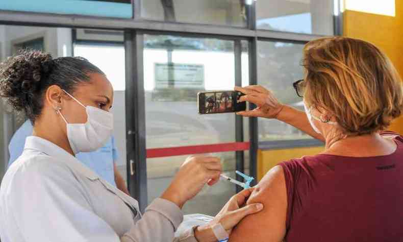 Maria Amelia Palhares, 67, registra o momento que recebe sua segunda dose da vacina(foto: Leandro Couri/EM/D.A Press)