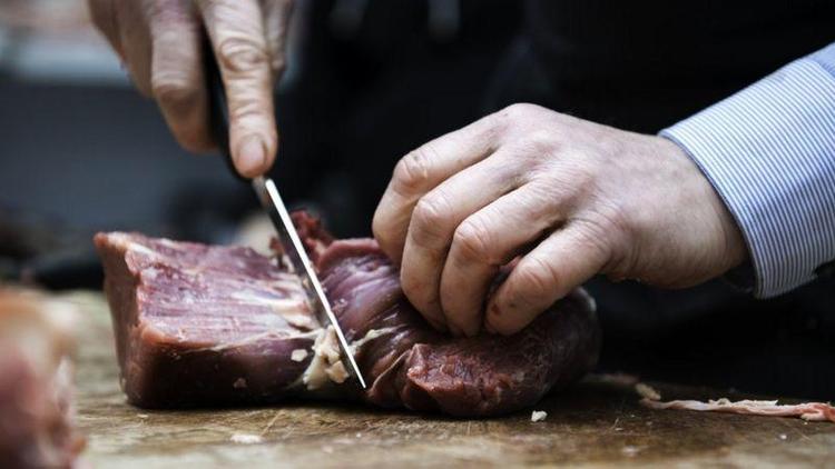 Mo de algum cortando carne sobre uma tbua