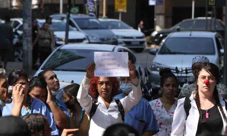 Mulher segurando uma placa escrito 'no sou guerreira, sou tcnica em enfermagem', na manifestao