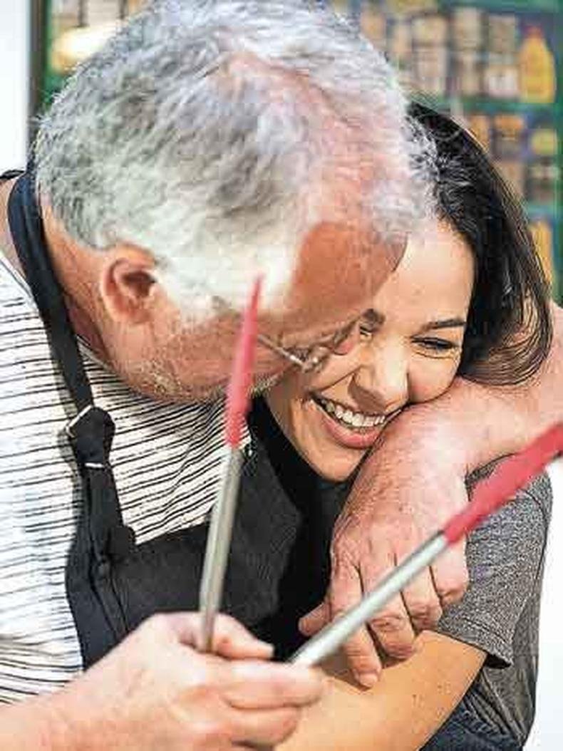 O chef Humberto Passeado, segurando uma pin�a de cozinha, abra�a Carol Machado
