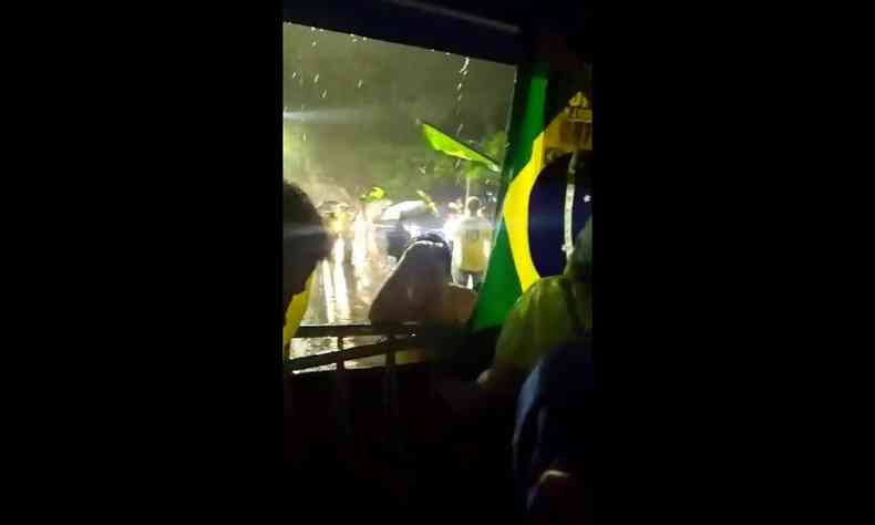 Bolsonaristas enfrentam chuva na raja com bandeira do brasil e bales verdes e amarelos