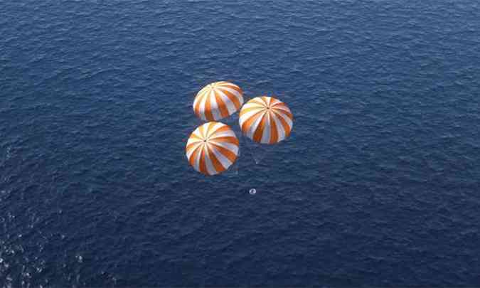 Simulao mostra a cpsula pairando no ar com trs para-quedas, enquanto se aproxima da gua(foto: Nasa/Simulao)