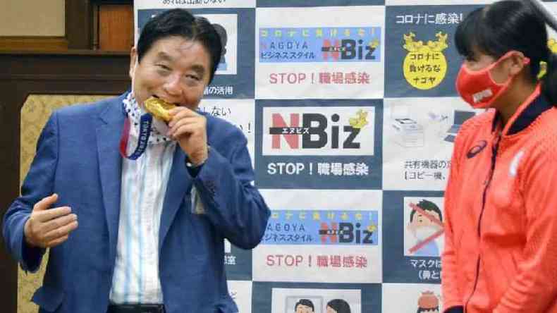 O prefeito Takashi Kawamura mordeu a medalha de Miu Goto durante um evento(foto: Kyoto/Reuters)