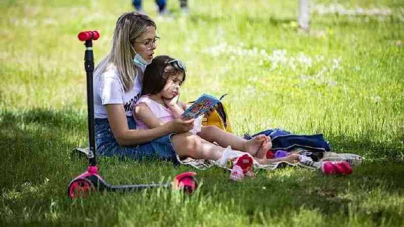 Menina lendo no colo da me em um parque
