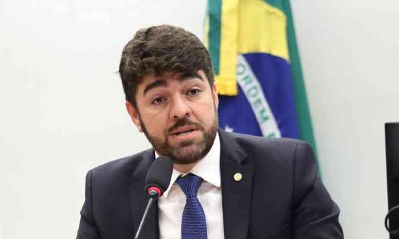 Deputado Federal Zé Vitor (PL-MG) fala ao microfone com uma bandeira do Brasil ao fundo
