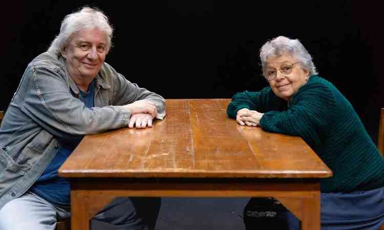 Marco Nanini e Camila Amado, sentados  mesa, olham para a cmera