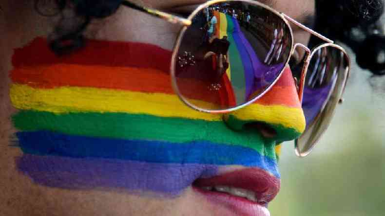 Mulher com a cara pintada com as cores da bandeira LGBT