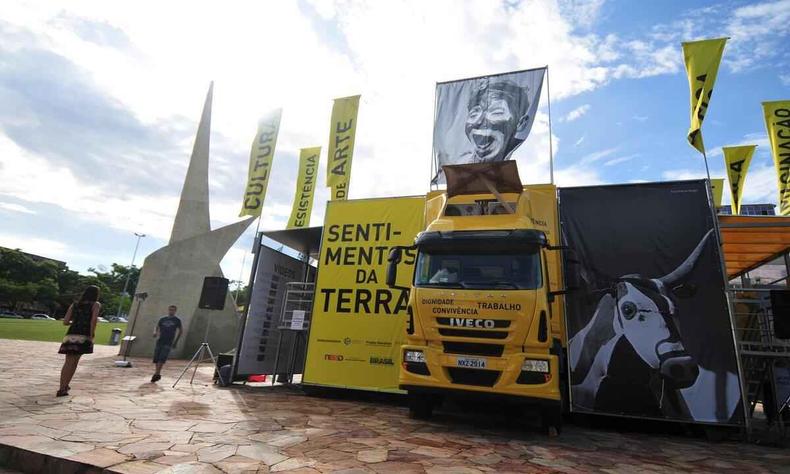 caminho que se transforma em museu ao lado de cartaz onde se leem as palavras sentimentos da terra. em volta do veculo h banners alusivos a exposio
