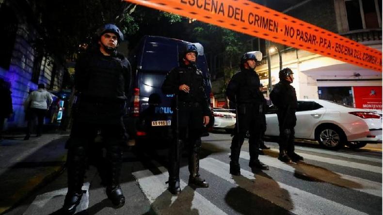 Foto noturna mostra policiais atrs de faixa de isolamento na rua