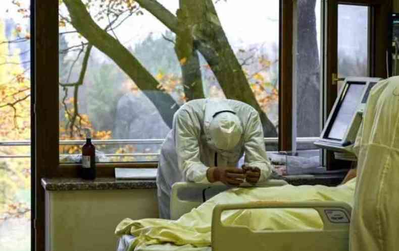 Homem perto do leito de paciente em hospital