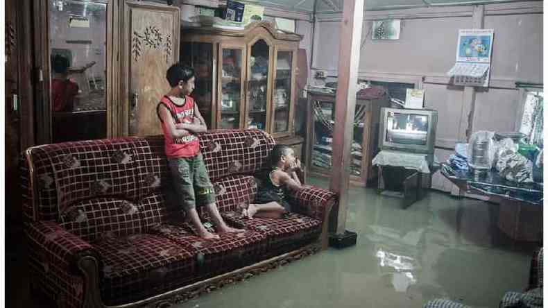 Crianas veem televiso em uma sala inundada