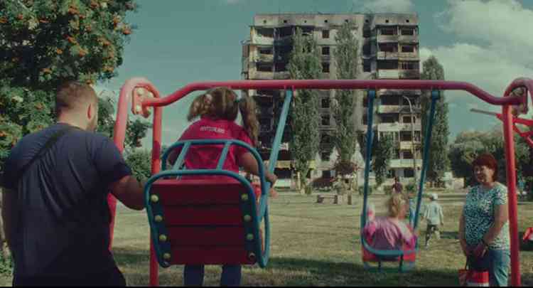 Adultos veem crianas brincar em gangorra em cena do filme In Ukraine