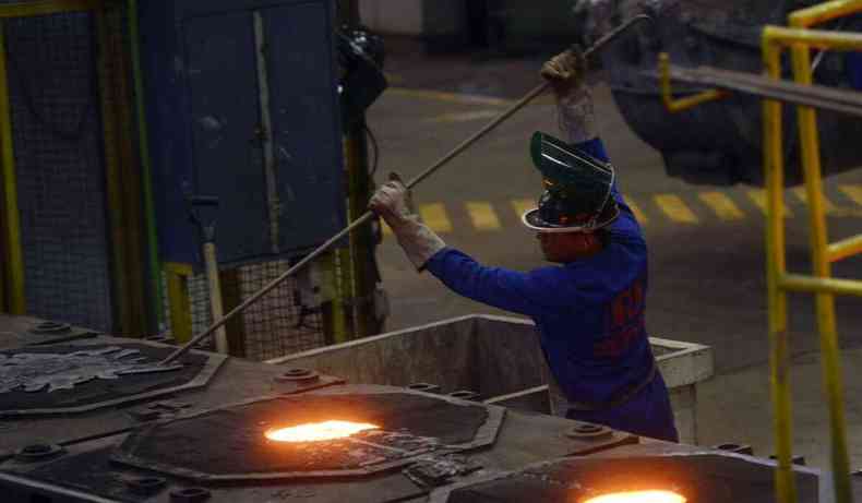 Foto de um operário trabalhando em uma indústria de aço
