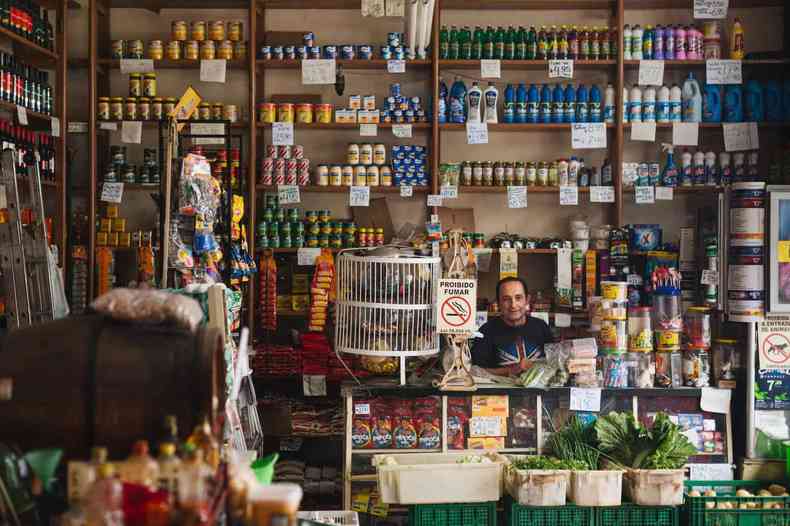 homem sentado na sua mercearia