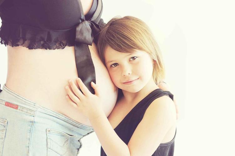 Criança segurando a barriga da mãe