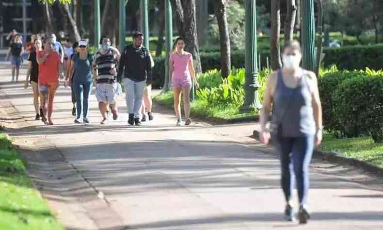 Pessoas caminhando na Praa da Liberdade, aps liberao do uso de mscaras em Minas Gerais. Na foto,  possvel ver uma mulher na frente, com mscara, e um grupo atrs, sem mscara