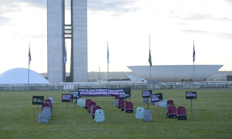 35 mochilas de diversas cores enfileiradas em frente ao Congresso Nacional em Braslia 
