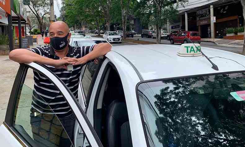 Motorista de txi Pedro Luiz Fernandes encostado na porta de seu carro