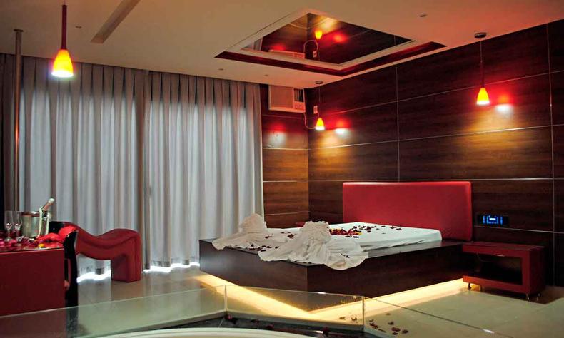Quarto de motel com luzes acesas e ptalas de flores sobre a cama de casal