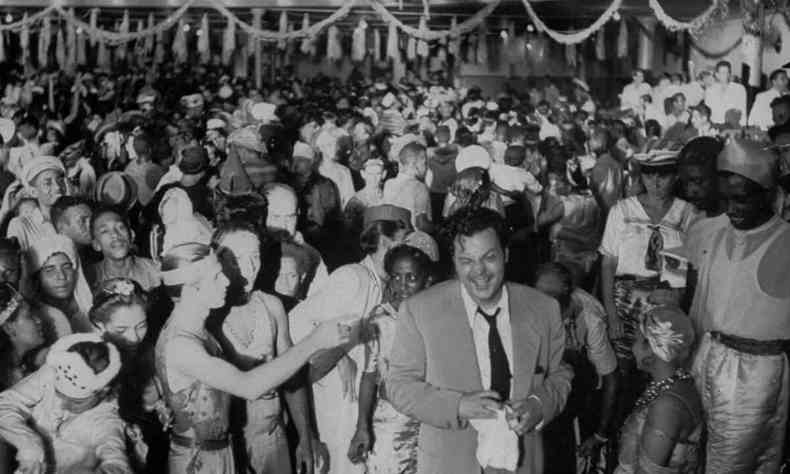 Orson Welles sorri no salo repleto de folies durante baile de carnaval